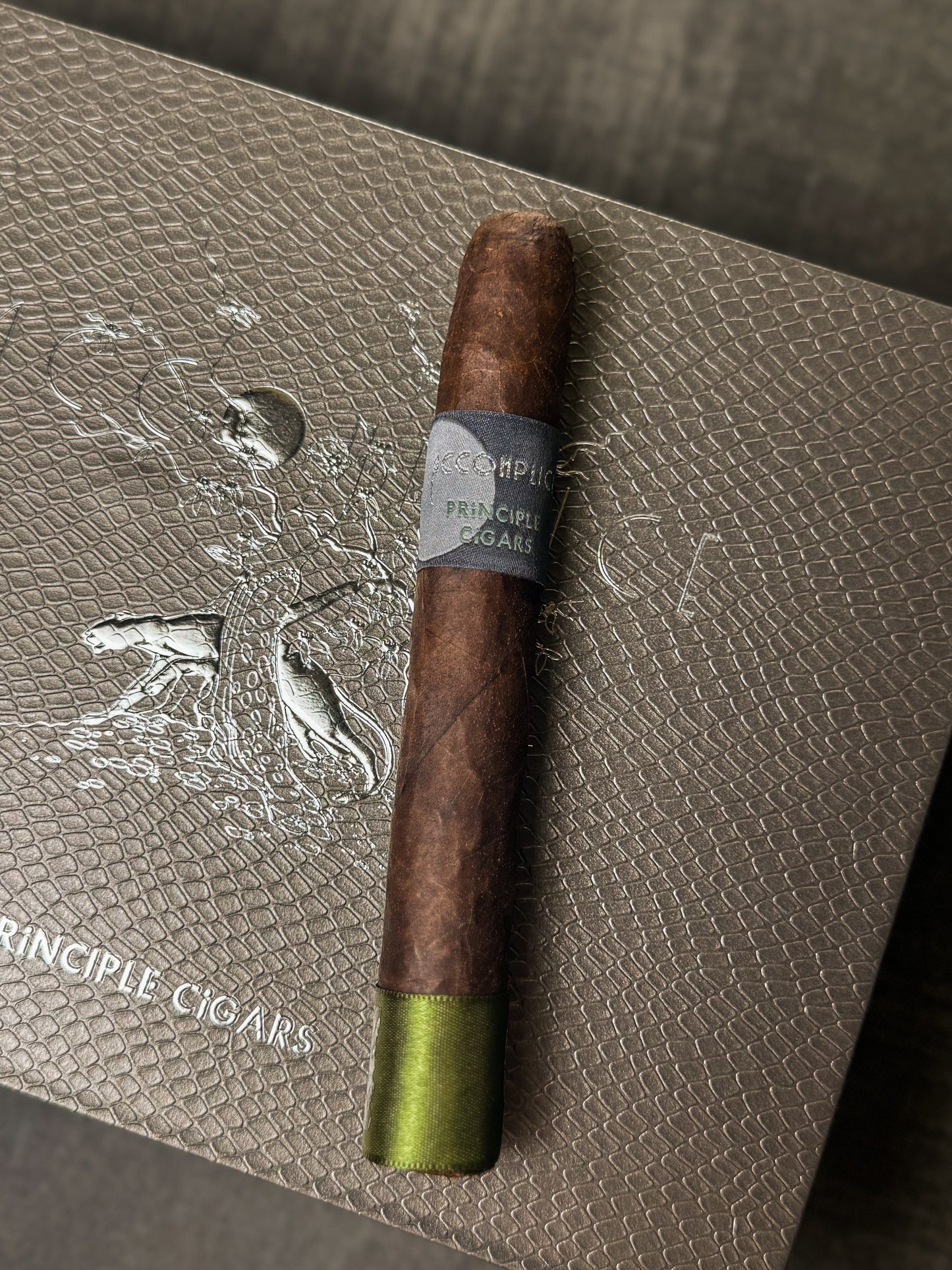 Cigar with green tip on a textured surface