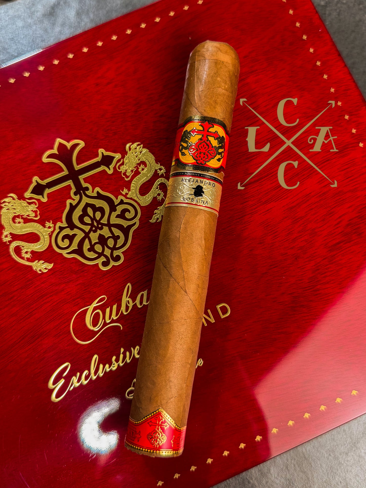 Cigar with a red band on a red box labeled 'Cuban Exclusive' with a logo.