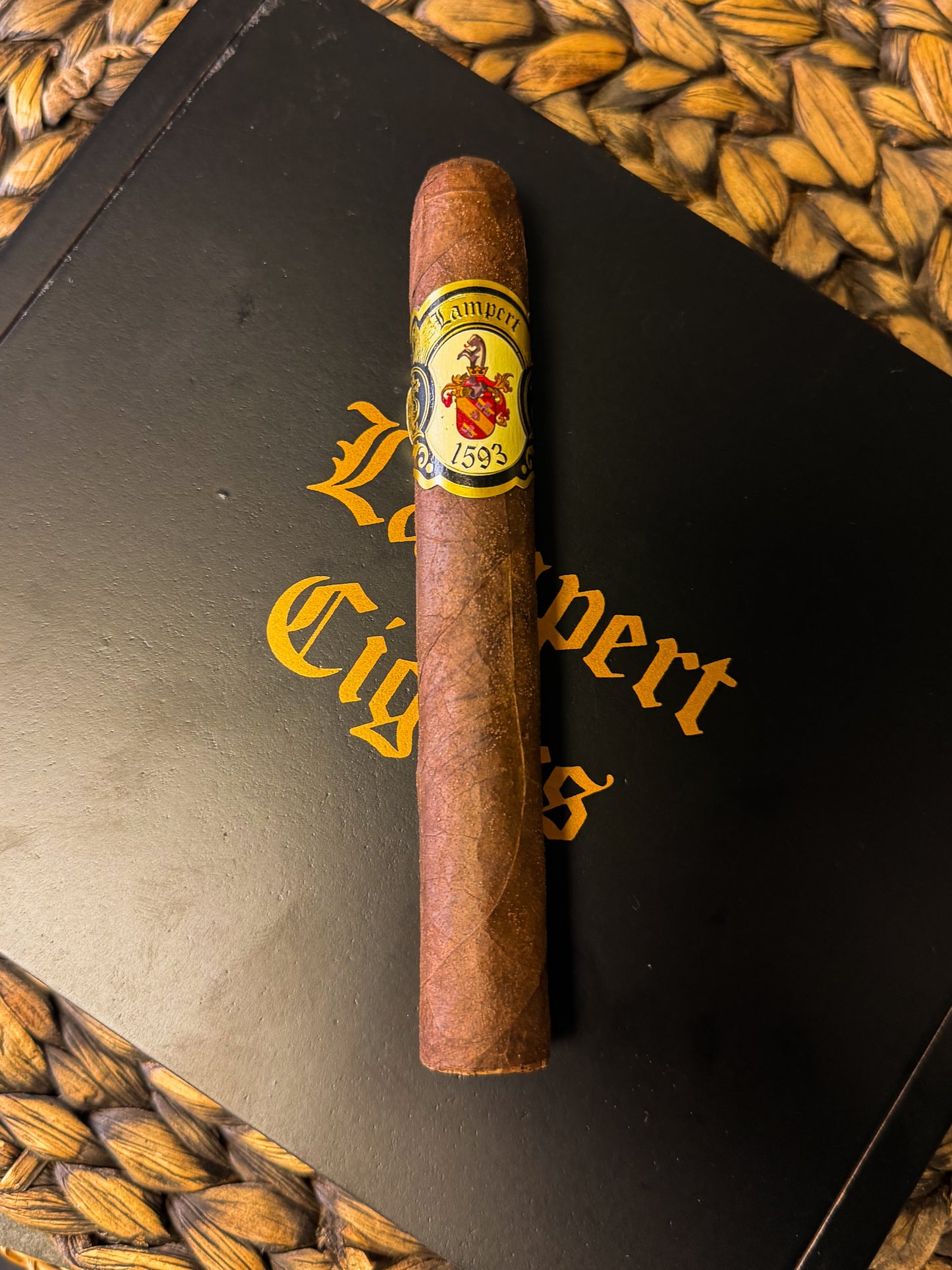 Cigar with a label on a black surface with 'Lampert Cigars' branding.
