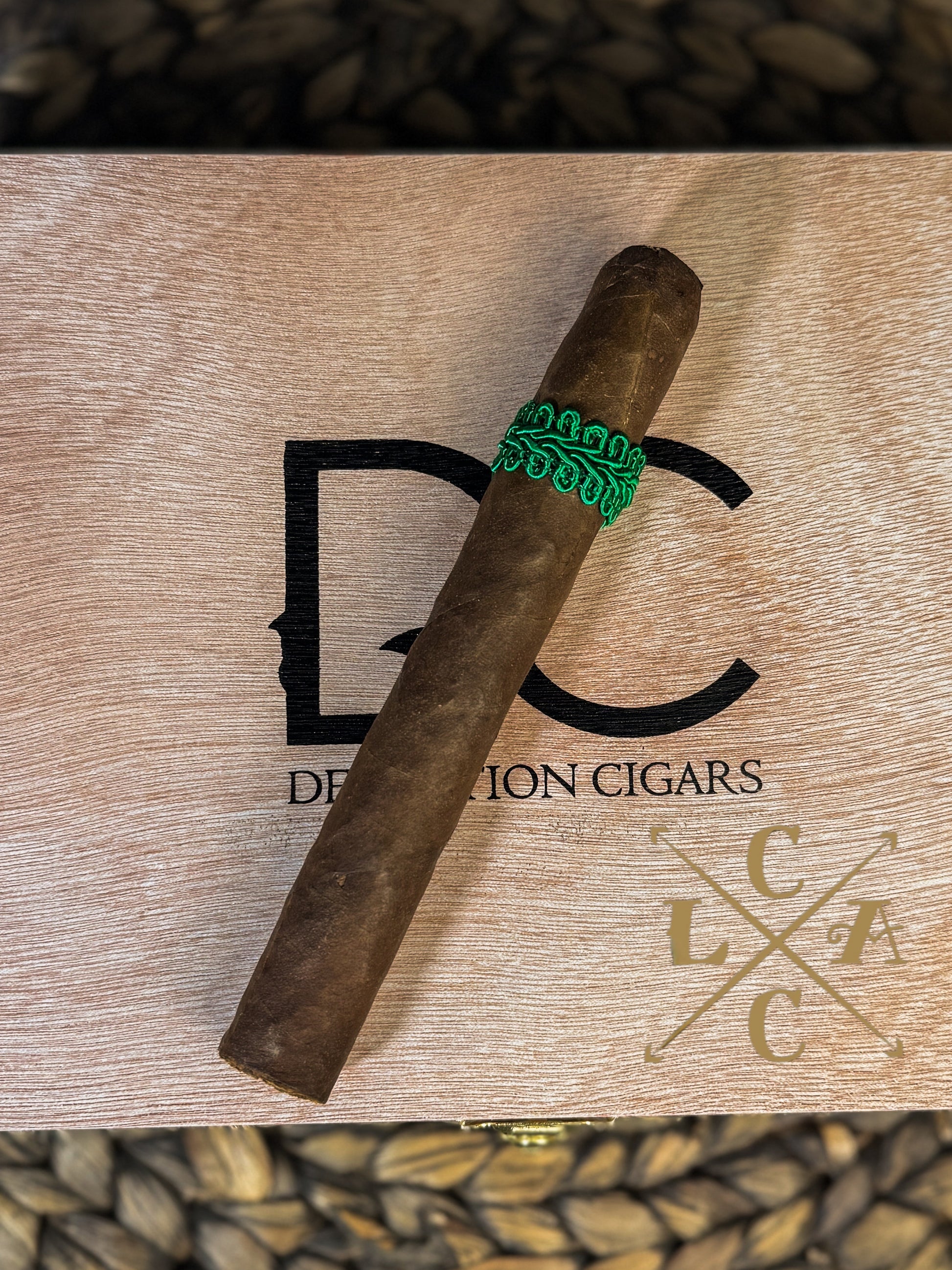 Cigar with a green band on a wooden box labeled 'DC Cigars' with a logo.