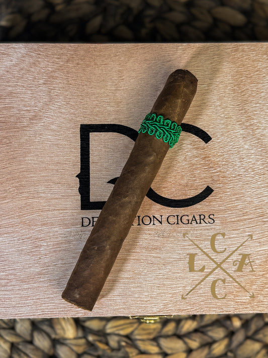 Cigar with a green band on a wooden box labeled 'DC Cigars' with a logo.