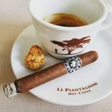 Cigar with a ring on a saucer next to a cup of coffee with a logo.