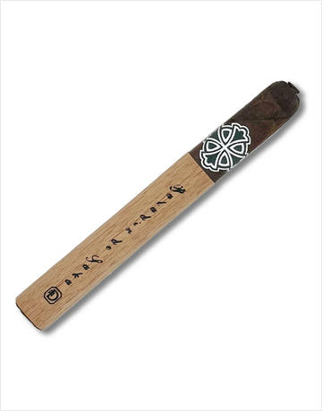A single cigar shown diagonally on a plain white background. The cigar has a light tan wood-textured body with black printed script and a dark brown wrapper section at the top featuring a white geometric emblem.