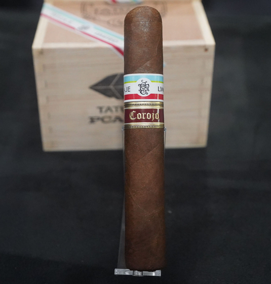 Cigar with a colorful band in front of a wooden box