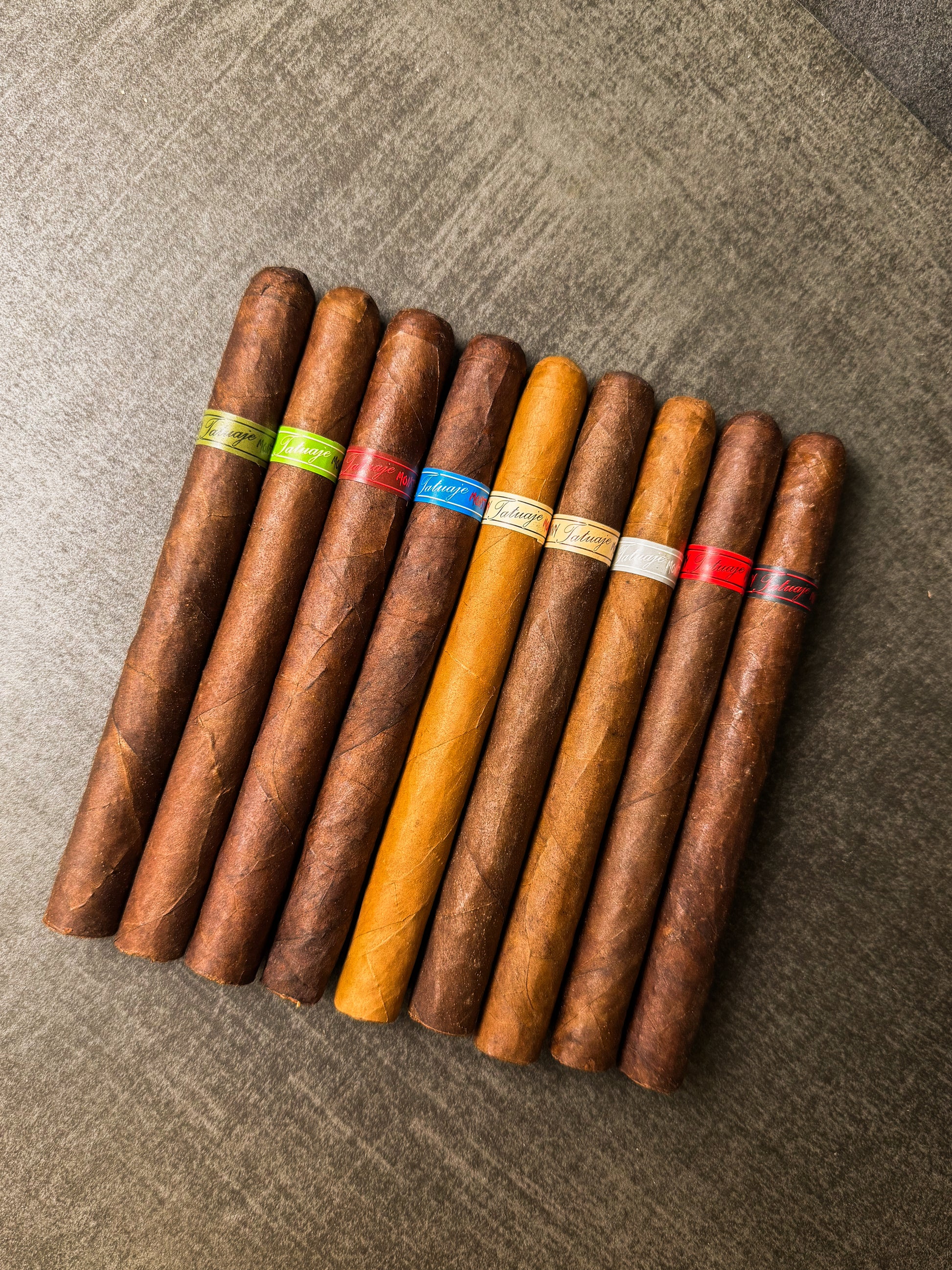 Assorted cigars with color-coded bands on a textured surface
